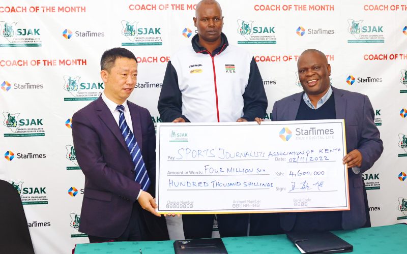 Startimes Kenya MD Andy Wang  (L) presents a cheque to SJAK president (R) Chris Mbaisi as the national volleyball women's team Malkia Strikers coach Paul Bitok looks on during the launch SJAK coach of the  month sponsored by Startimes Kenya at a Nairobi hotel on November 2, 2022. PHOTO/ SJAK