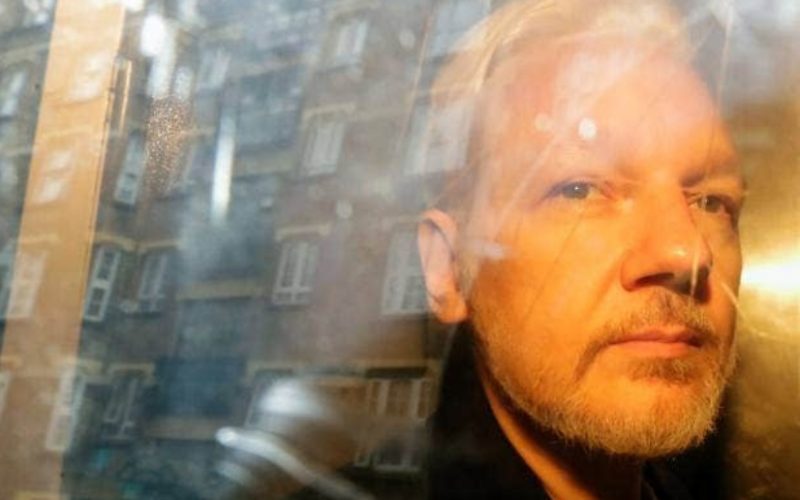 Buildings are reflected in the window as WikiLeaks founder Assange is taken from court. PHOTO/AP