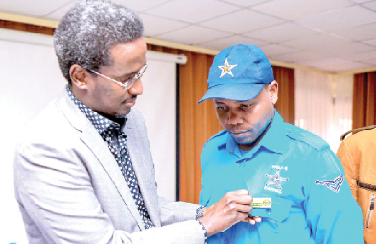 Private Security Regulatory Authority (PSRA) Director General Fazul Mohammed attaches a Guard Force Number on the uniform of one of the private security officers. PHOTO/Print