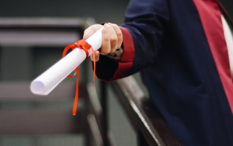 A graduate holding a white scroll.