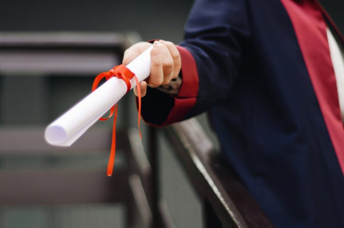 A graduate holding a white scroll.