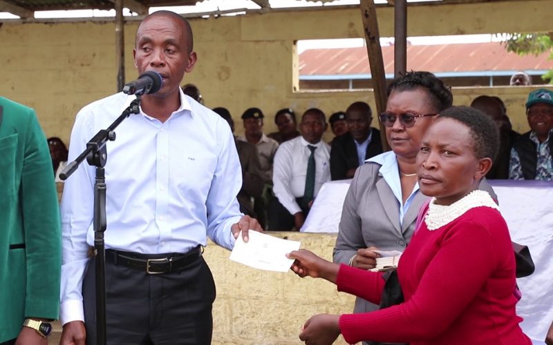 Kiambu governor Kimani Wamatangi hands over bursary cheques to beneficiaries at Premier Bag grounds in Juja, Kiambu County. PHOTO/Mathew Ndung'u