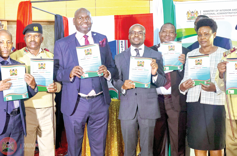 Immigration PS Prof Julius Bitok (centre) with his Interior counterpart Raymond Omollo (in glasses) during the unveiling of new guidelines for ID card issuance at the Kenya School of Government, yesterday g. PHOTO/Philip Kamakya