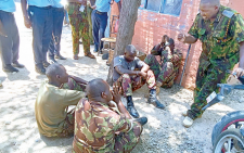 Turkana Central Sub-County Police Commander Samuel Boit (right, standing) with four KDF soldiers at Lodwar Police Station where they were arrested after assaulting and disarming an officer. PHOTO/Print