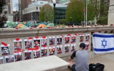 A person prays in front of photos of hostages posted at Columbia University in New York City, New York, on April 24, 2024. PHOTO/David Dee Delgado/Reuters