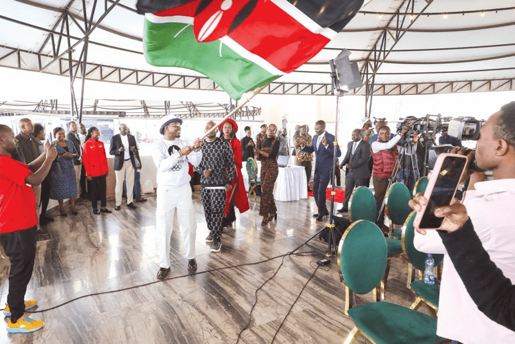 Sports Cabinet Secretary Ababu Namwamba (with flag) lead designers and guests in a dance during award ceremony for winners of Team Kenya ceremonial dress. INSET: Rosemary Runyenje whose attire won the opening ceremony catergory. PHOTO/SPORTPICHA