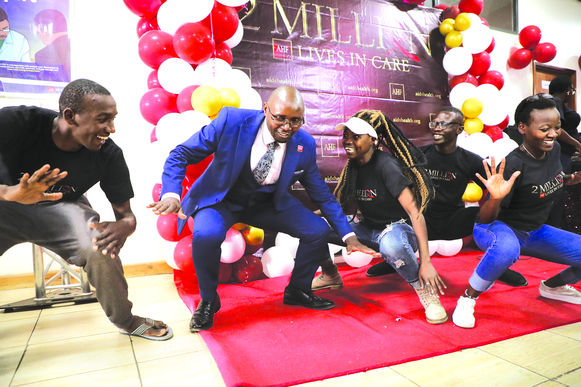 AIDS Healthcare Foundation (AHF) Country Director Dr Samuel Kinyanjui (second left) joins members of the Florics Club initiative, Mathare in song and dance during the official opening of the AHF wellness clinic at Eastleigh in Nairobi and celebrating 2 million lives in HIV care globally. PHOTO/Bernard Malonza