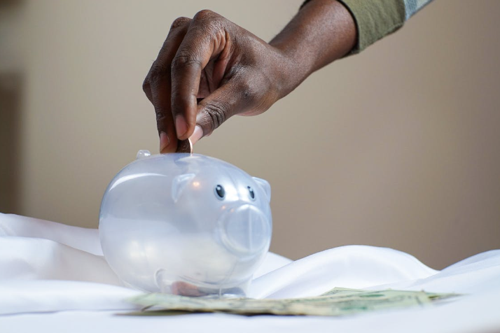 A person inserting a coin in a piggy bank. PHOTO/Pexels