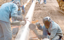 Workers weld a pipeline equipment. PHOTO/Print