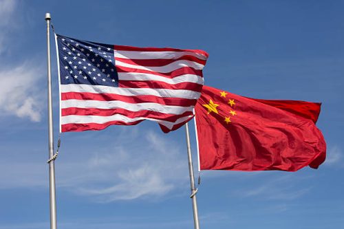 Symbolic photo of China-American relations, the flag of the United States of America and the flag of the Republic of China fly together on flag poles next to each other on a sunny, windy day.