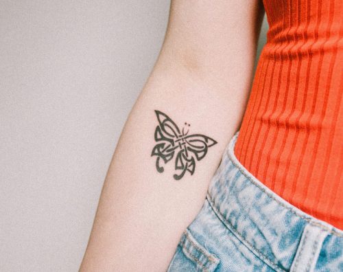 Woman arm with a butterfly tattoo holding apple. Image used for representational purposes only. PHOTO/Pexels