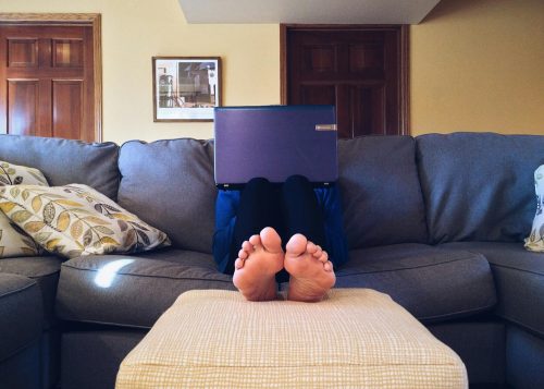 A person sitting on a couch while using a laptop computer. Image used for illustration purposes only. PHOTO/Pexels