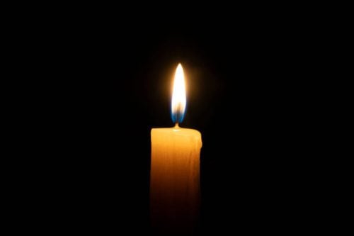 An orange candle burns on a black background with a reflection copy space: Image used for illustation only: PHOTO/Pexels