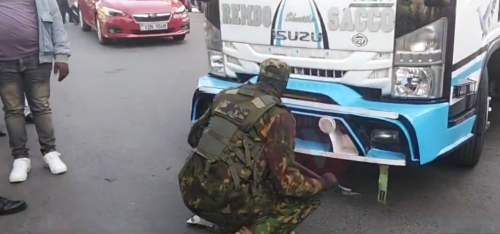 A police officer removes a number plate from a matatu blocking a road in Nairobi CBD. PHOTO/Screengrab by People Daily Digital