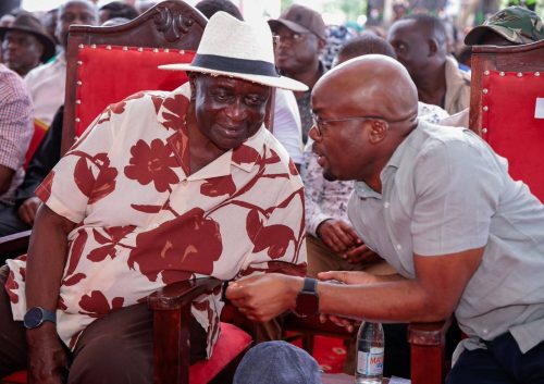 Interior PS Raymond Omollo shares a moment with ODM Party leader Oburu Oginga during the burial ceremony of Nyando MP Jared Okello's mother in Nyando, Kisumu County. PHOTO/Viola Kosome